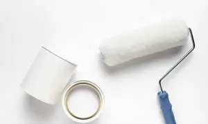 Rullo e barattolo di pittura bianca pronti per dipingere su pittura al quarzo.