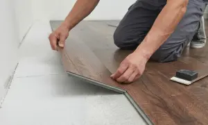 Un operaio in posa spc. di un nuovo pavimento in laminato effetto legno.