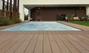 Ponte in legno effetto grana, ideale per esterni, circonda una piscina coperta. I requisiti dei pavimenti per esterni sono soddisfatti da questo materiale resistente e bello.