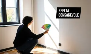 Persona sceglie colori per come pitturare una casa moderna, tenendo campioni di vernice contro il muro bianco illuminato dal sole.