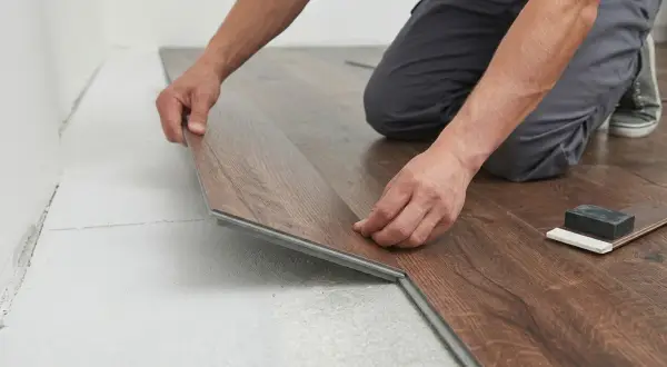 Un operaio in posa spc. di un nuovo pavimento in laminato effetto legno.