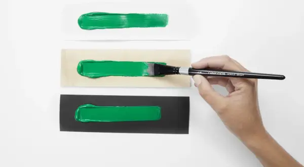 Pennello stende vernice acrilica su carta bianca, legno e nera. La vernice acrilica a cosa serve? A creare effetti vibranti su diverse superfici.