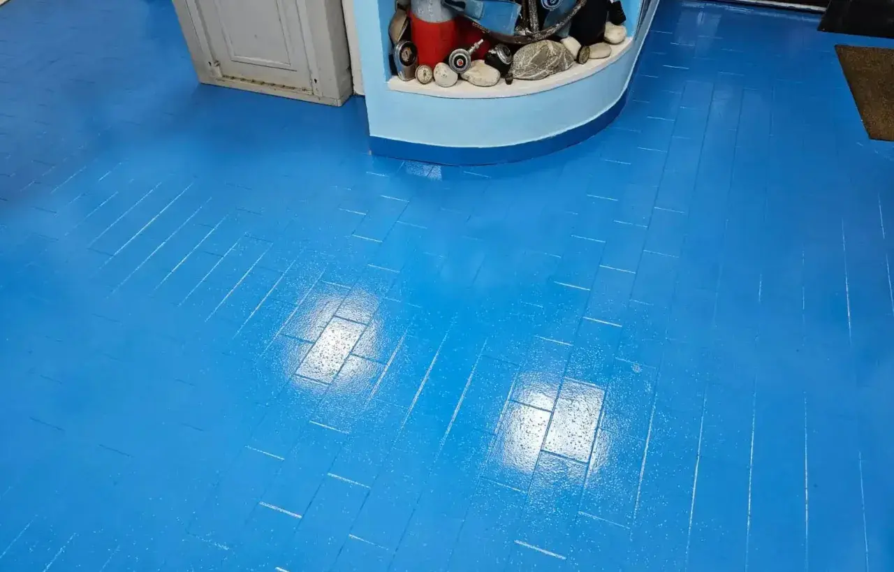 Pavimento blu brillante, effetto parquet, appena finito di lavorare la resina. Riflessi luminosi sulla superficie liscia.