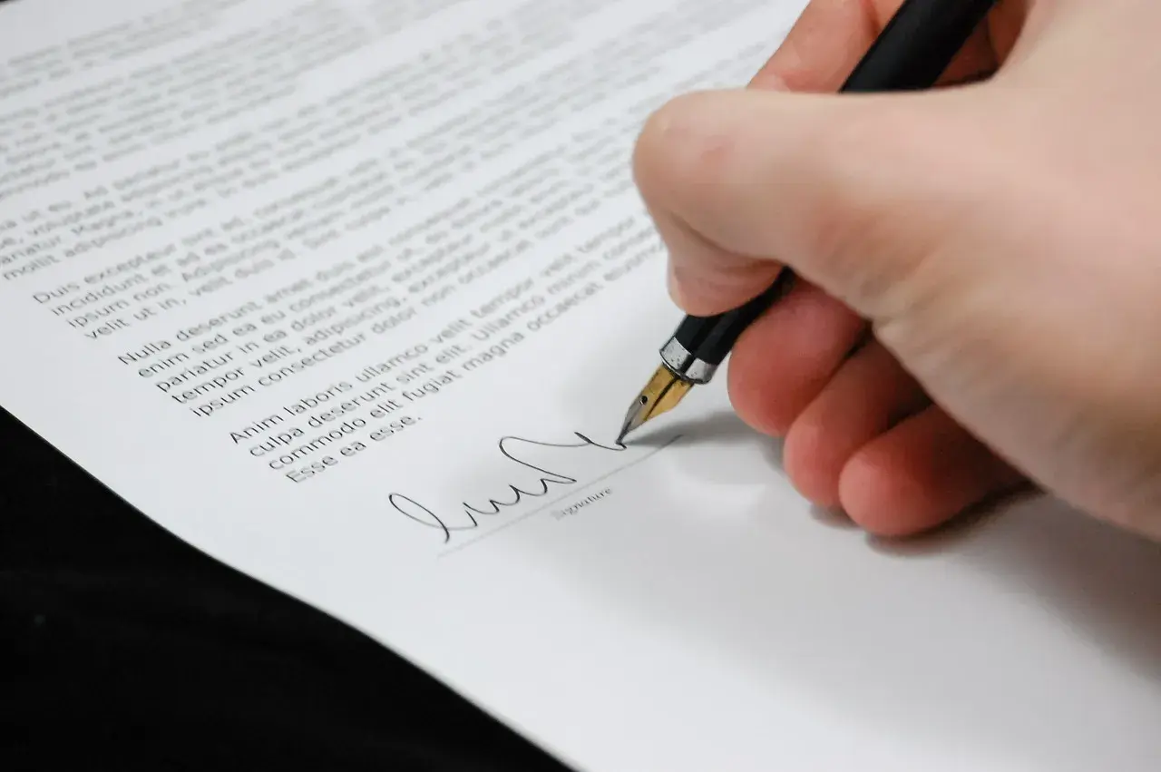 Firma su un documento, con una penna stilografica che scrive. Il peritale significato di un accordo si concretizza in questo gesto.