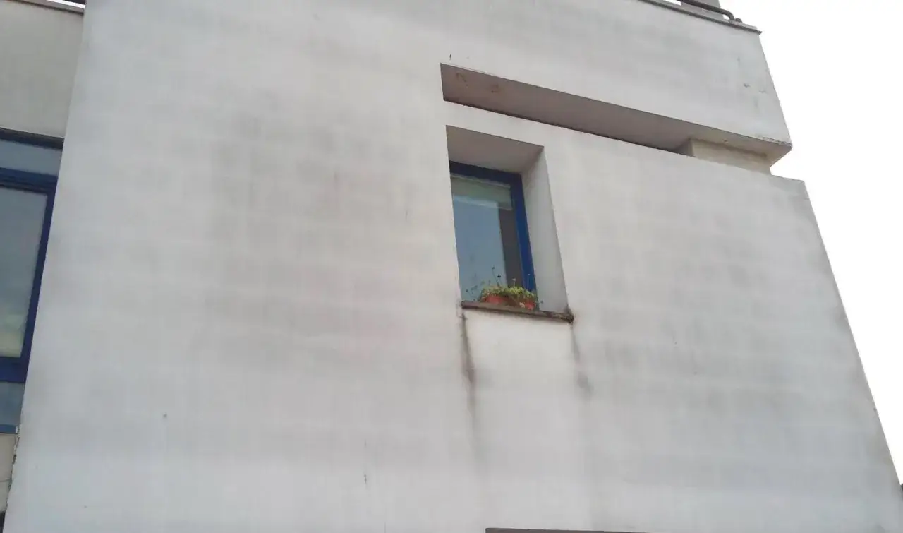 Facciata con evidenti difetti cappotto termico, macchie scure e segni di umidità attorno alla finestra.