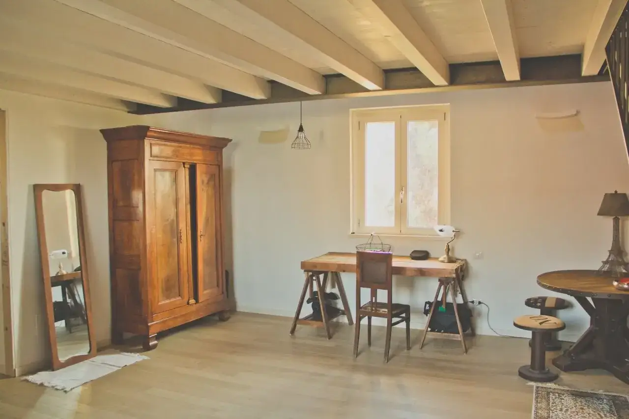 Arredare casa in campagna fai da te: armadio antico, scrivania rustica e specchio a figura intera creano un angolo studio accogliente.