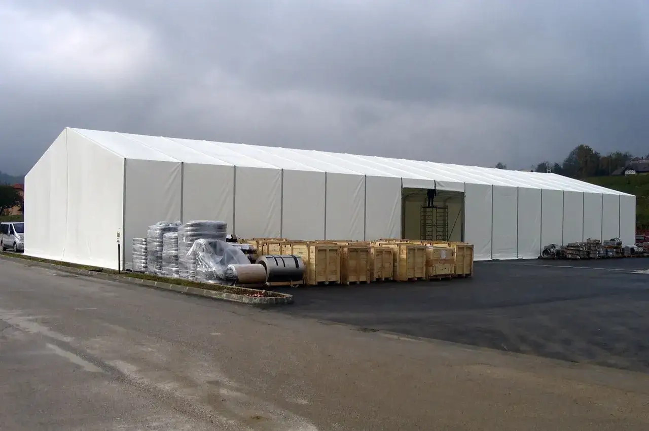 Ampia tensostruttura bianca, con materiali stoccati all'esterno, in attesa dei permessi per l'installazione.