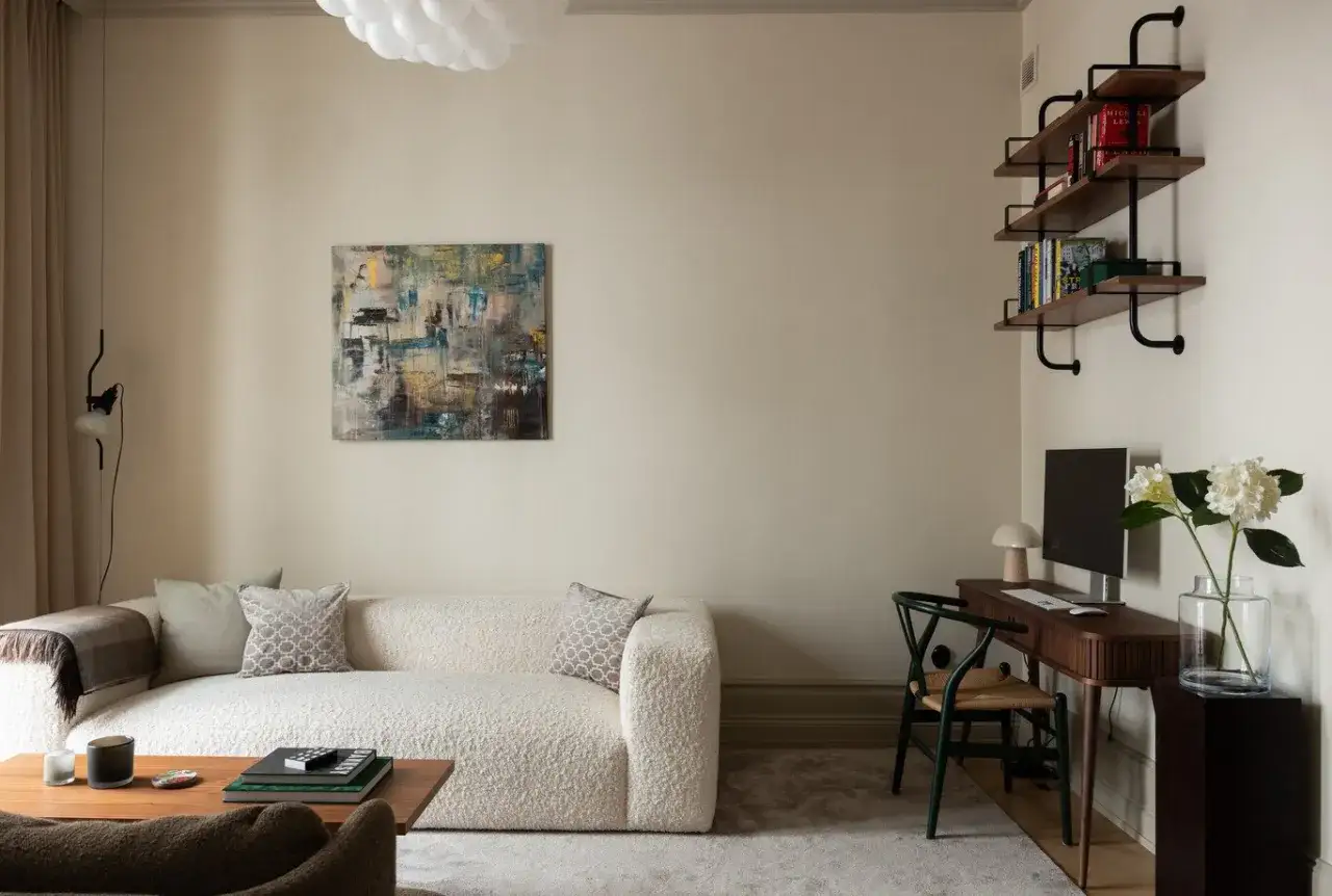 Soggiorno con divano boucl&eacute; bianco, tavolino in legno e un perfetto abbinamento colori crema nelle pareti e nei tessuti.