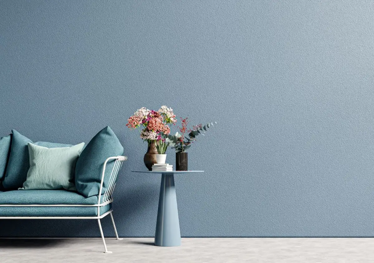 Divano blu e tavolino con fiori su muro azzurro, ispirazione per come pitturare una casa moderna.