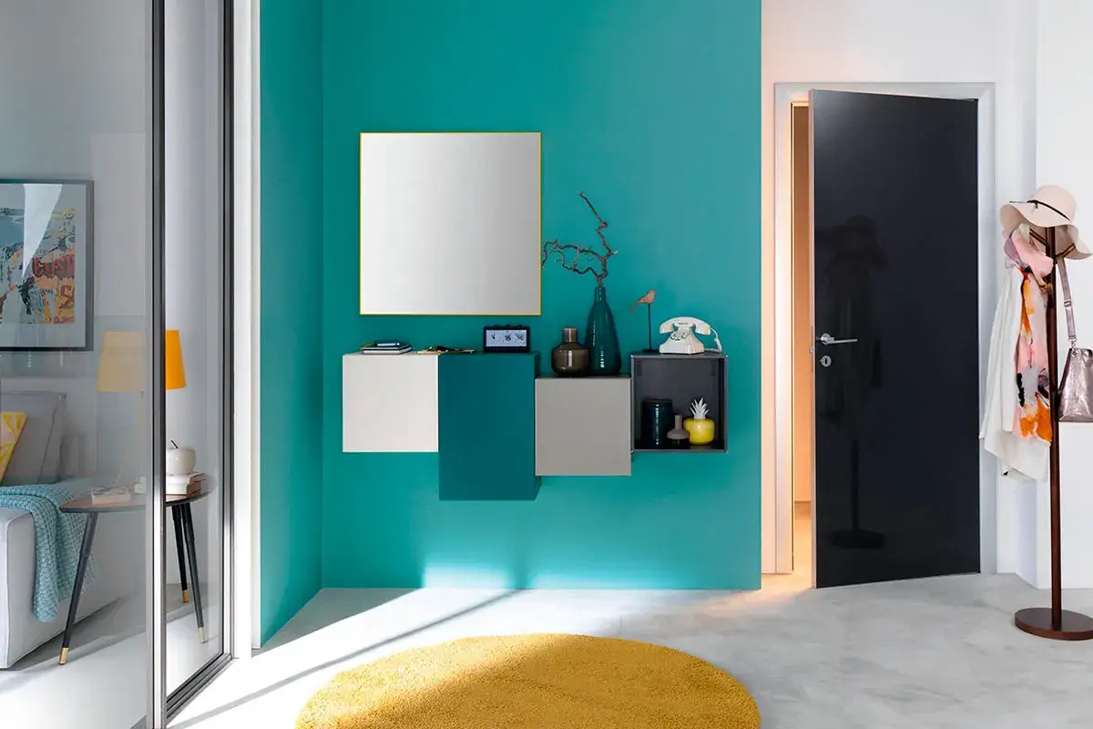 Modern entryway with teal wall, floating shelves, mirror, and black door.