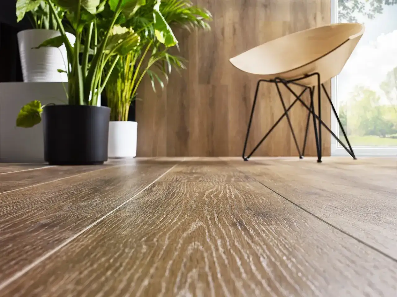 Un elegante pavimento SPC effetto legno, con piante verdi e una sedia di design. Scopri cos'è il pavimento SPC per un tocco moderno.