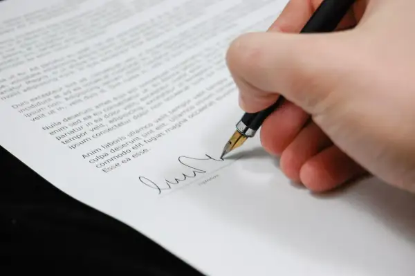 Firma su un documento, con una penna stilografica che scrive. Il peritale significato di un accordo si concretizza in questo gesto.